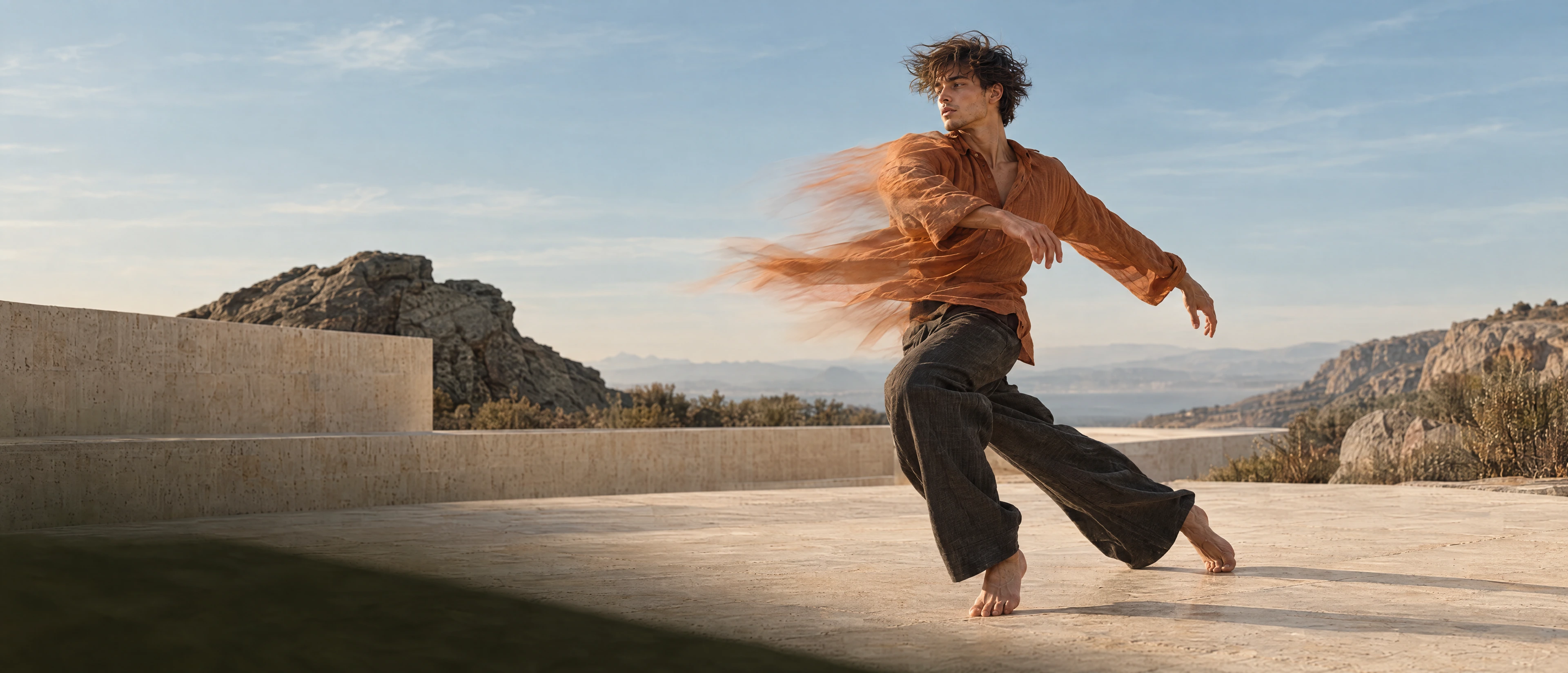 A male dancer turning on limestone, copper fabric moving with him.